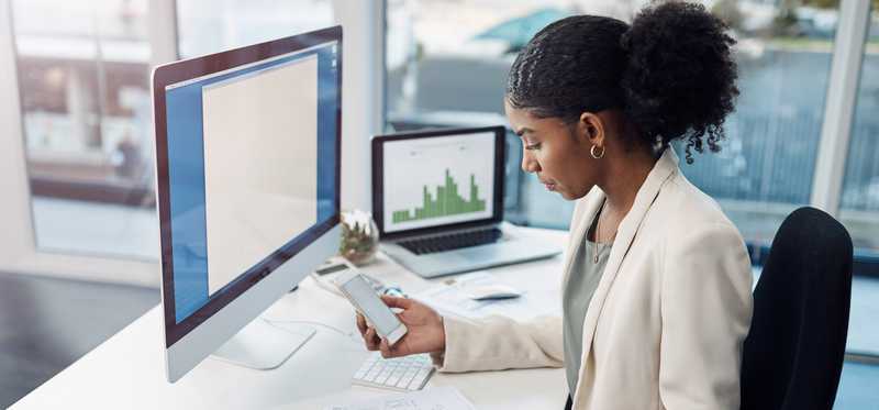 Person looking at phone while at desk in office cubicle.