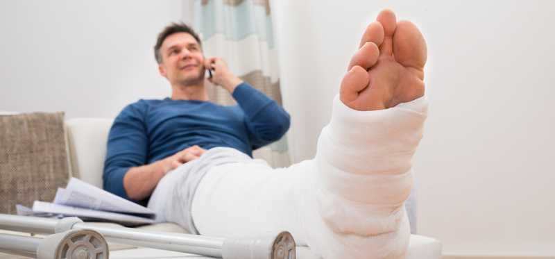 Person sitting on couch with leg in a cast.