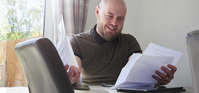 Person sitting at desk and reviewing paperwork.
