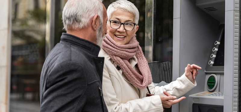 Two people talking at an ATM.