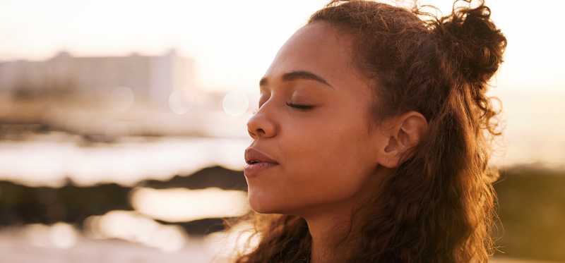 Close-up of adult breathing consciously while outside with eyes closed.
