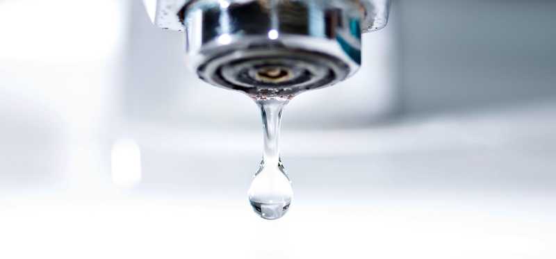 A faucet dripping a water droplet