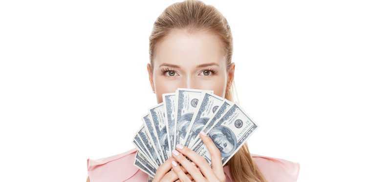 A person peers over fanned-out $100 bills they are holding.