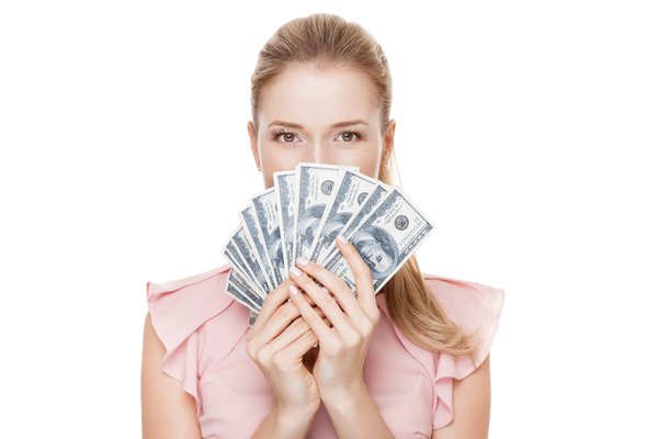 A person peers over fanned-out $100 bills they are holding.