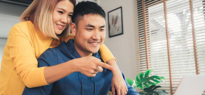 Two people smiling and looking at laptop.
