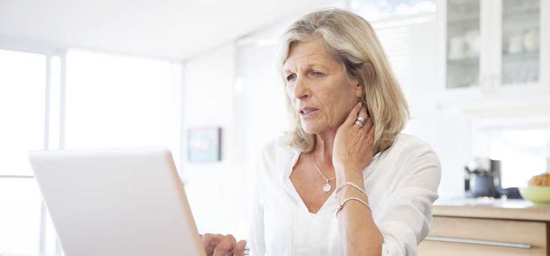 Mature woman concerned looking at laptop screen