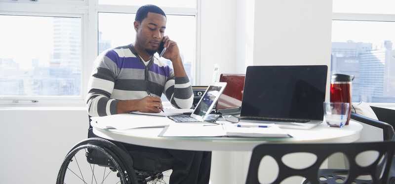 Person talks on phone in bright city office.