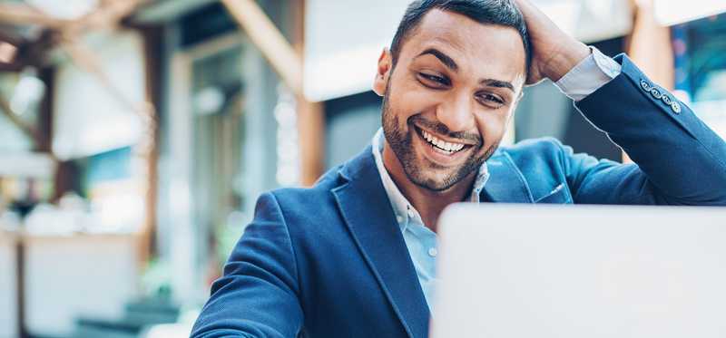 Person smiling widely while looking at laptop.