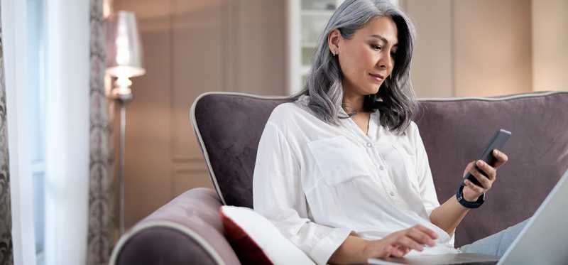 Person sitting on couch and looking at a phone.