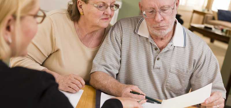 An elderly couple looking at paperwork with an advisor.