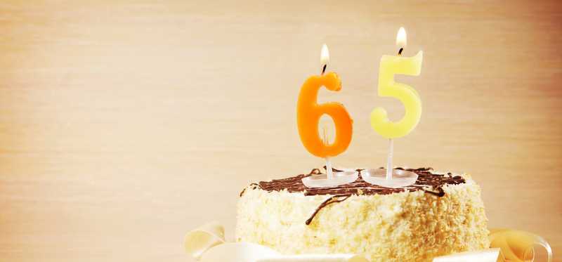 A birthday cake with candles numbered 65.
