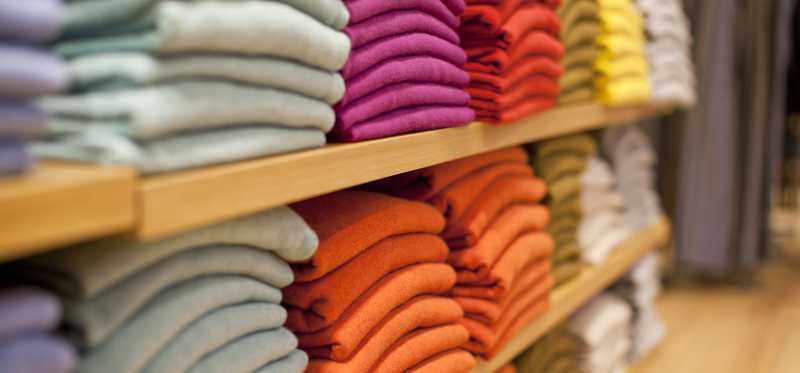 Colorful sweaters on shelves.