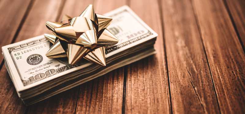 A stack of $100 bills with a gold bow on top.
