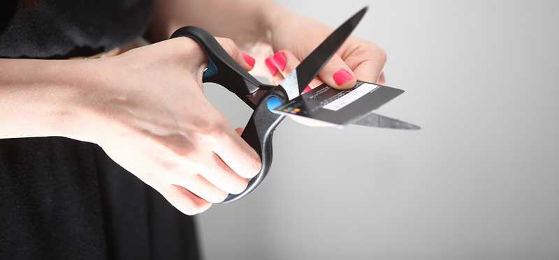 A woman cuts up her debit card.