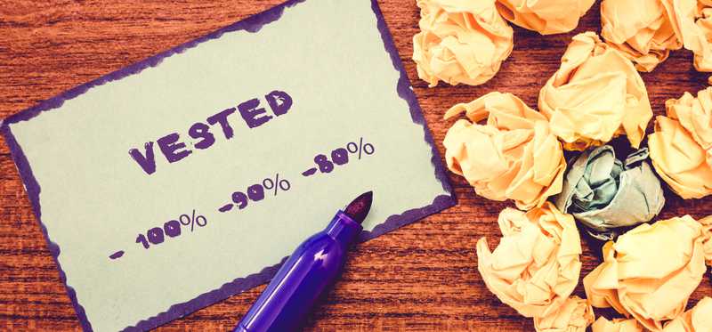 Purple marker with card saying Vested and different amounts next to crumpled papers.