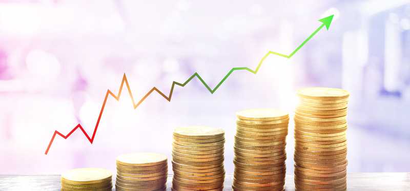 Stacks of coins increasing in height with rising stock arrow over them.