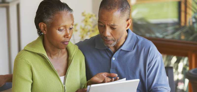 Two people review documents in front of laptop at home.