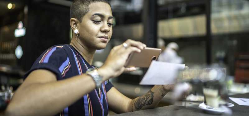 Adult takes picture of check to deposit funds in bank account with smartphone.