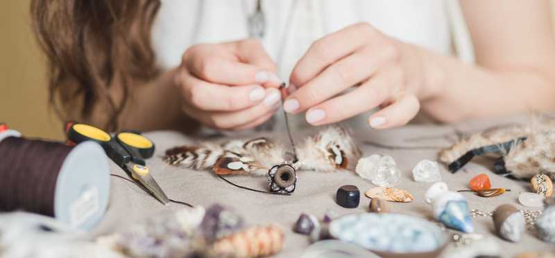 Person crafting with shells and feathers.
