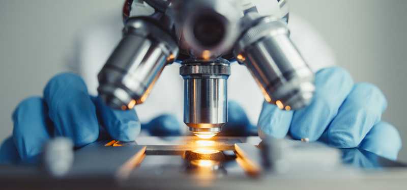 Man looking at something under a microscope.
