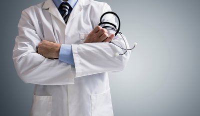 A doctor standing in his white coat with arms crossed.