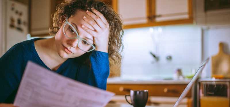 Stressed person in glasses is looking at bill.