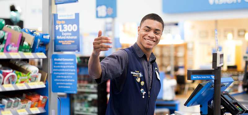 Smiling Walmart cashier signaling for next customer.