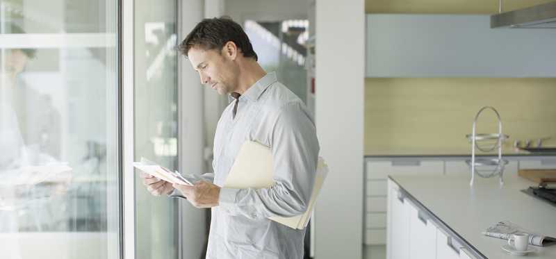 Person looking at documents while standing in kitchen.