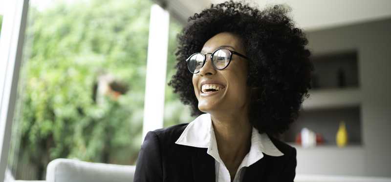 Person wearing glasses smiles while holding phone.