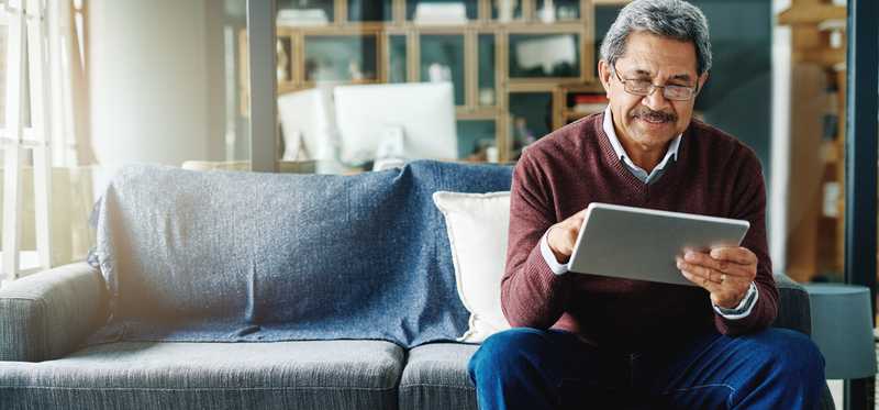 Person sitting on couch and using tablet.