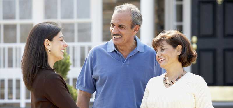 People shaking hands in front of a house.