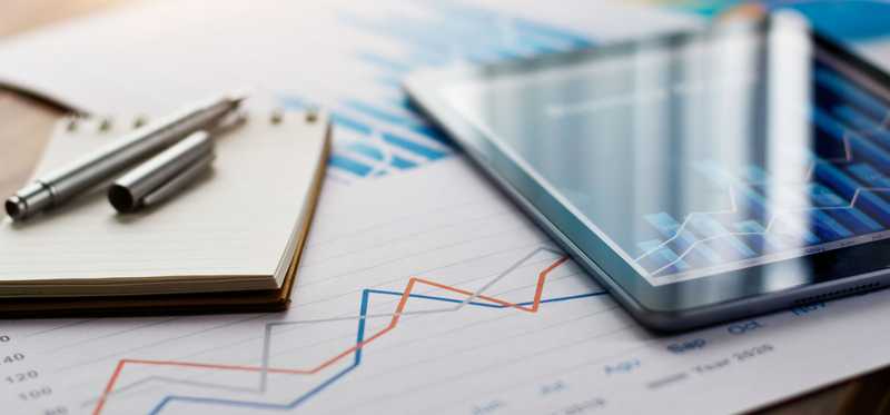 Business document report on paper and tablet with sales data and financial business growth graph on table background.