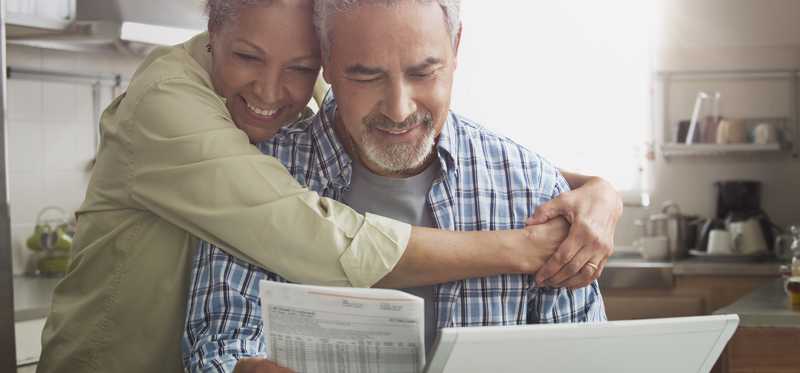 Two people hugging and smiling while looking at paperwork.