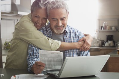 Two people hugging and smiling while looking at paperwork.