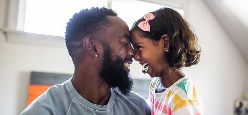 Two people smile with their noses and foreheads pressed together.