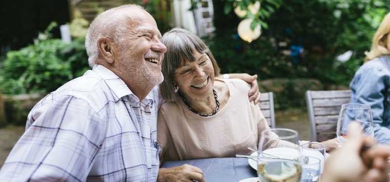 Two happy people eating outside.