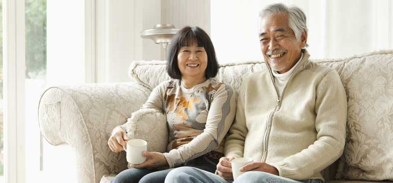 Two people sitting on couch with coffee mugs.