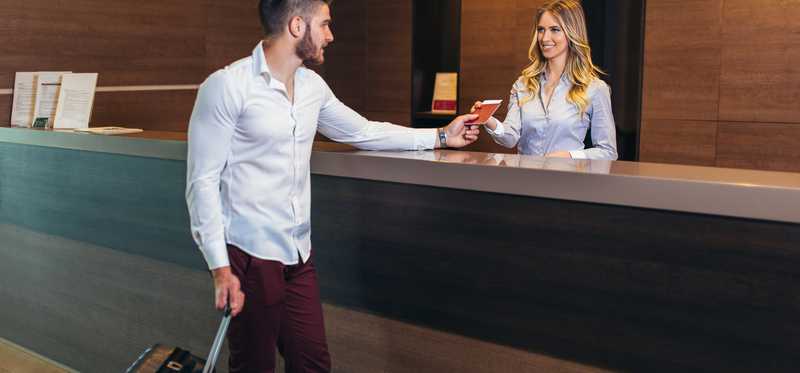 Woman employee talking to male guest at reception desk.