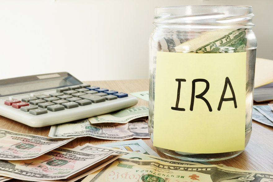 Jar of money labeled IRA sitting next to calculator.