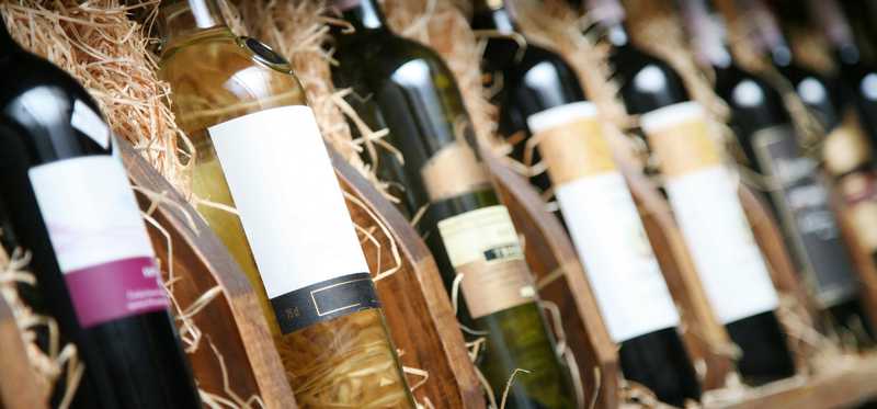 Assorted bottles of wine sitting in hay-filled crates.