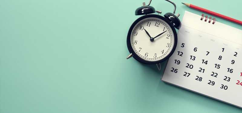 Alarm clock next to a calendar.
