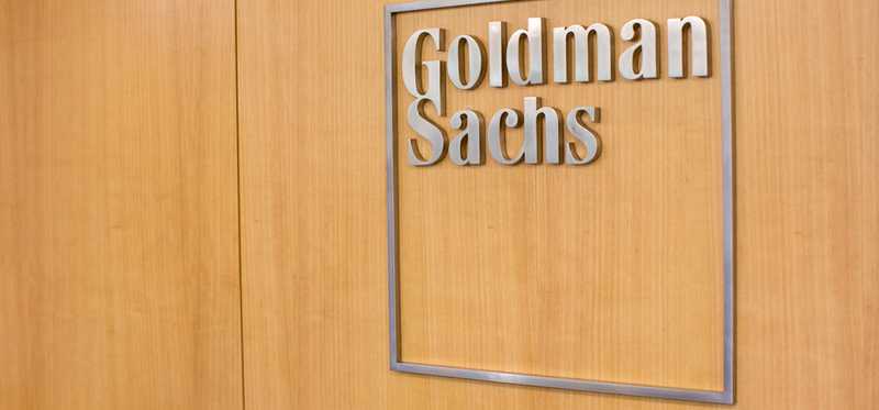 A metal Goldman Sachs sign on a wooden door.
