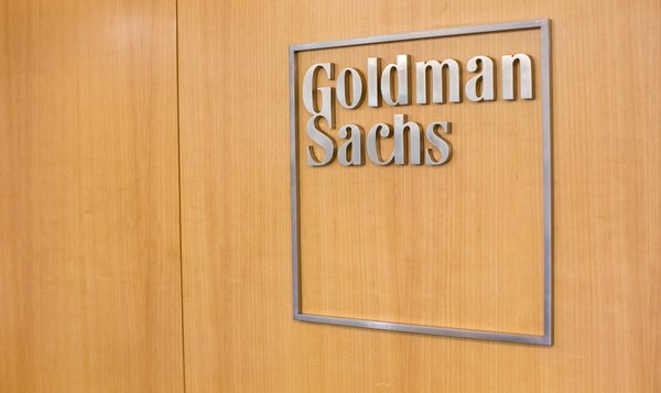 A metal Goldman Sachs sign on a wooden door.