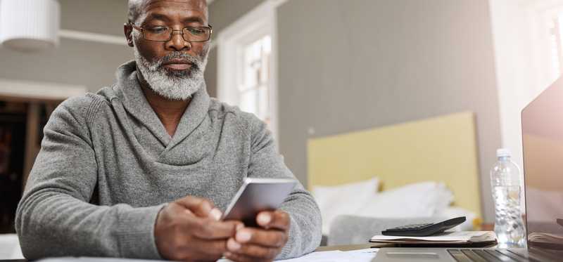 Older man looking at phone while sitting at desk