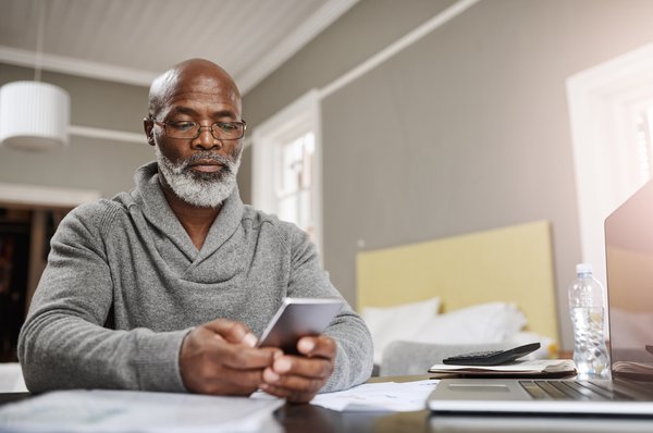 Older man looking at phone while sitting at desk