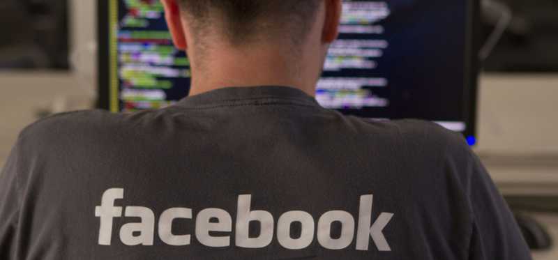 A Facebook engineer writing code on laptop at his desk.