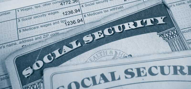 A Social Security card lying atop a W2 tax form, highlighting payroll taxes paid.