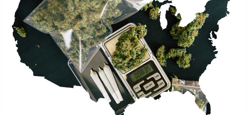 A black silhouette of the United States, partially filled in with baggies of cannabis, rolled joints, and a scale.
