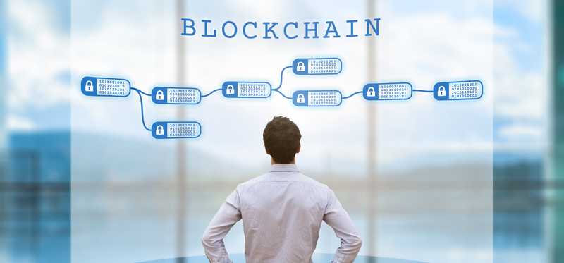 A businessman looking at an encrypted blockchain on a digital screen.