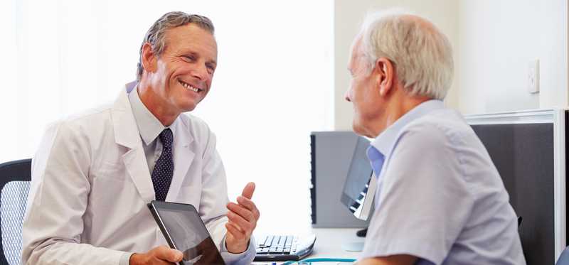 A doctor using a tablet to consult with a patient.